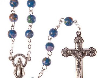 May include: A silver rosary with blue and white beads. The rosary features a silver crucifix with a figure of Jesus Christ and a silver charm of the Virgin Mary.