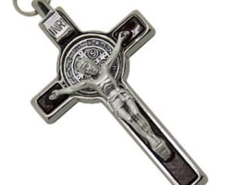 May include: Silver metal crucifix pendant with a dark wood-like finish. The crucifix features a depiction of Jesus Christ and a Saint Benedict medal with the inscription "INRI".