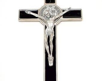 May include: A silver and black crucifix with a depiction of Jesus Christ on the cross. The cross has a black background and a silver frame. The crucifix is a religious symbol.