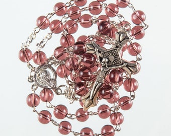 May include: A purple glass rosary with a silver crucifix featuring the inscription "INRI".