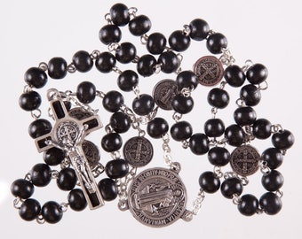 May include: A black wooden rosary with silver beads and a silver crucifix. The crucifix features a depiction of Jesus Christ. The rosary also includes a silver medal with the image of Saint Anthony of Padua.