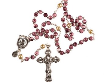 May include: A purple and white rosary with a silver crucifix and a silver pendant featuring a depiction of the Virgin Mary. The rosary beads are made of glass.