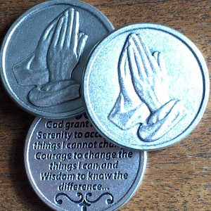 May include: Three silver-toned metal tokens with a praying hands design on two of the tokens. The third token has the text "God grant Serenity to accept things I cannot change. Courage to change the things I can, and Wisdom to know the difference..."