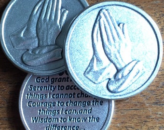 May include: Three silver-toned metal tokens with a praying hands design on two of the tokens. The third token has the text "God grant Serenity to accept things I cannot change. Courage to change the things I can, and Wisdom to know the difference..."