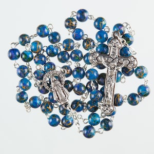 Rosario con perline a motivi blu. Realizzato a mano con robusti collegamenti in filo metallico tra ogni perla.