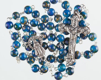 May include: A blue and gold rosary with a silver crucifix and a silver charm of the Virgin Mary. The beads are made of wood and have a marbled pattern.