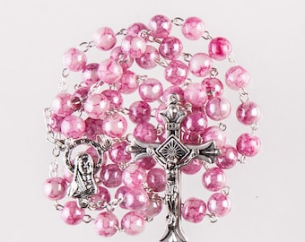 May include: A rosary with pink and white marbled beads. The rosary features a silver crucifix with the figure of Jesus and a silver pendant with a depiction of the Virgin Mary. The beads are strung on a silver chain.