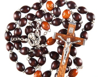 May include: A brown wooden rosary with a silver crucifix and a silver charm of the Virgin Mary. The beads are oval shaped and have a dark brown color. The crucifix is simple and has a silver figure of Jesus on it.