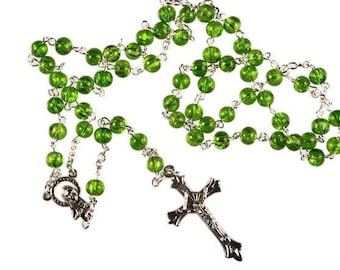May include: A green glass rosary with a silver crucifix and a silver charm. The rosary beads are strung on a silver chain.