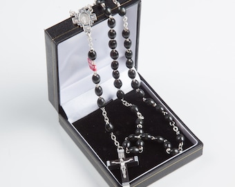 May include: A black wooden rosary with silver beads and a silver crucifix in a black velvet box.