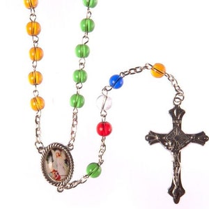 May include: A silver rosary with colourful glass beads and a silver crucifix. The beads are green, orange, yellow, blue, and clear. The crucifix has a silver image of Jesus on the front.
