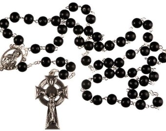 May include: Black wooden rosary beads with a silver Celtic cross pendant. The cross features a depiction of Jesus on the crucifix.