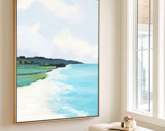 May include: Large framed canvas art featuring a coastal landscape. The artwork depicts a beach with turquoise water, white sand, and green vegetation under a light blue sky with clouds. The frame is gold-toned, and the painting hangs on a white wall.