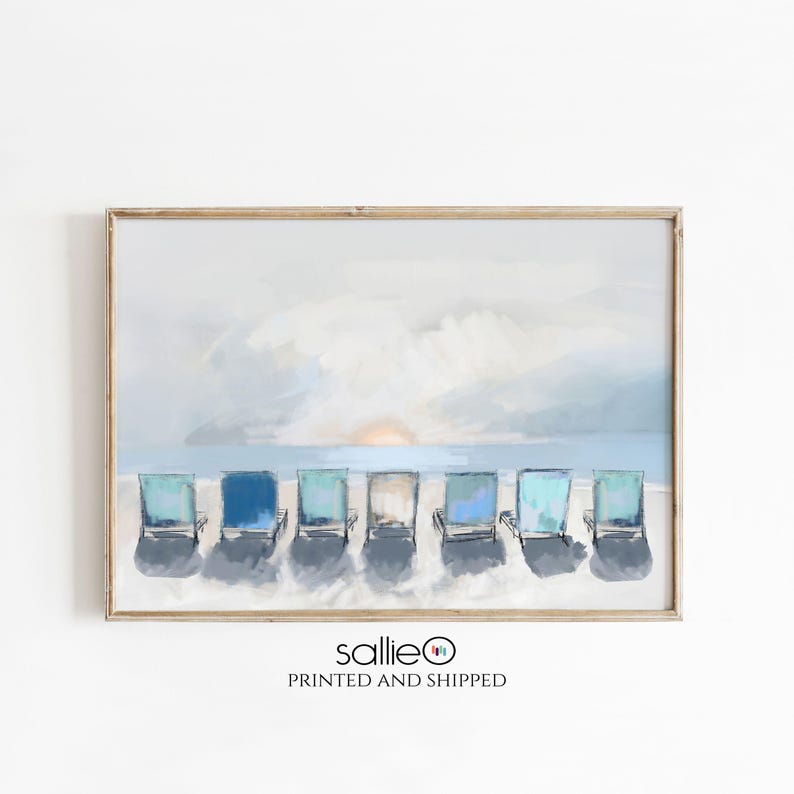 May include: A framed print featuring a beach scene with seven blue and teal beach chairs lined up on the sand. The background shows a light blue sky, ocean, and a setting sun. The print has a wooden frame.