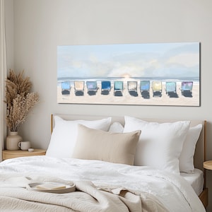 May include: A rectangular canvas print depicts a beach scene with ten colorful beach chairs lined up on the sand. The chairs are various shades of blue, green, and purple, facing the ocean under a light blue sky with a setting sun.