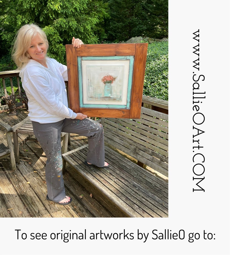 May include: A woman holds a framed painting of a floral arrangement in a vase. The painting has a light blue background and a wooden frame. The woman is wearing a white shirt and gray pants. The text "www.SallieOArt.COM" is visible in the image. To see original artworks by SallieO go to: www.SallieOArt.COM