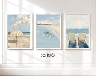 May include: Three framed paintings of beach scenes. The leftmost painting shows a yellow and white striped beach umbrella on a sandy beach. The middle painting shows a blue ocean with a sandy beach and a group of birds in the water. The rightmost painting shows two beach chairs on a sandy beach with a blue ocean in the background.