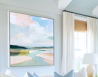 May include: Abstract landscape painting in a white frame. The artwork features a pastel color palette with shades of blue, pink, green, and yellow. The painting depicts a river flowing through a landscape with a cloudy sky.