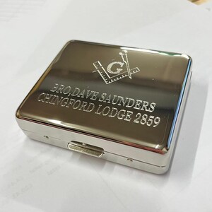May include: Silver cigarette case with an engraved Masonic symbol, the name "Bro. Dave Saunders" and "Chingford Lodge 2859".