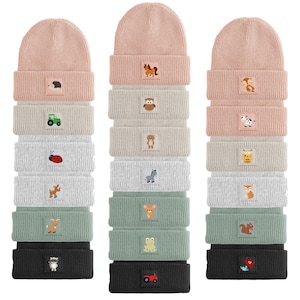May include: A collection of knitted beanies in shades of pink, beige, grey, green, and black. Each beanie has a small embroidered patch with a different animal or object, including a hedgehog, horse, owl, bear, ladybug, deer, mouse, frog, or tractor.
