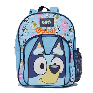 May include: Bluey and Bingo character backpack with a blue background and a large blue dog face on the front. The backpack has a mesh side pocket and the name "Oscar" is printed in orange on the front.