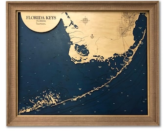 May include: A framed wooden bathymetric map of the Florida Keys, Florida. The map features light wood landmasses set against a deep blue water background, with a compass rose and the text FLORIDA KEYS FLORIDA printed in the upper left corner.
