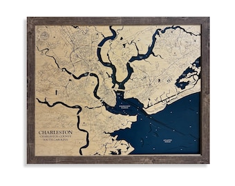 May include: A framed wooden map of Charleston, South Carolina, featuring a light tan landmass with dark blue water details. The map displays Charleston Harbor and surrounding areas with text reading Charleston, Charleston County, South Carolina.