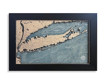 May include: A framed 3D bathymetric map of Long Island and the surrounding coastal areas. The map features layered wood cutouts for landmasses and blue-toned water depths with white contour lines, text labels, and a compass rose.
