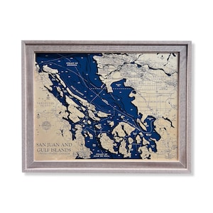 以下が含まれることがあります： サンフアン諸島とガルフ諸島の木製フレーム地図。青い海とベージュの大陸。ジョージア海峡、フアンデフカ海峡、テキスト「サンフアン諸島とガルフ諸島、アメリカ合衆国-カナダ」が含まれています。