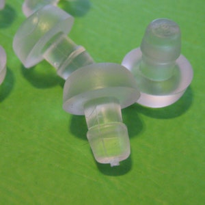 Może przedstawiać: Zbliżenie na przezroczyste, plastikowe zatyczki do uszu. Zatyczki do uszu są zaprojektowane tak, aby idealnie pasowały do ​​kanału słuchowego i blokowały hałas.