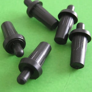 May include: Five black plastic furniture leg tips with a round base and a small, round, black tip. The tips are designed to protect floors from scratches.