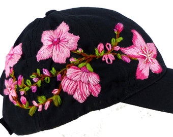 Pink cherry blossoms floral hand embroidered black cotton baseball cap with beading detail. Pony tail hole, velcro adjustable tab, one size.