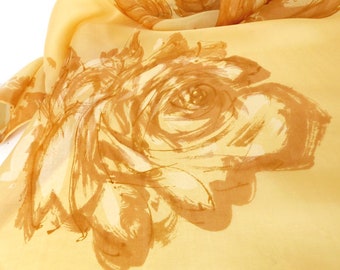 May include: A yellow silk scarf with a brown floral print of a single rose.
