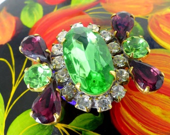 Centro de cristal verde brillante con detalles de cristal en forma de lágrima de color violeta. Broche magnético para bufanda Mag TAK™ Botón trasero de terciopelo violeta.