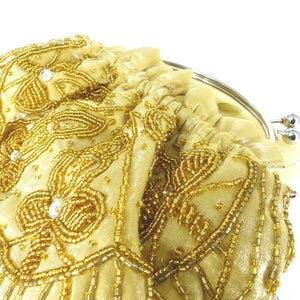 Puede incluir: Un bolso de mano de cuentas doradas con cierre de plata. El bolso est&aacute; decorado con un patr&oacute;n floral y tiene un detalle de flecos.