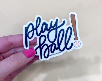 May include: White sticker with black script that says "Play Ball!" with a brown baseball bat and a red baseball with white stitching.