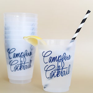May include: A set of clear plastic cups with a black and white striped straw. The cups have the text "Campfire Cocktail" printed on them in blue. A lemon wedge is in the cup on the right.