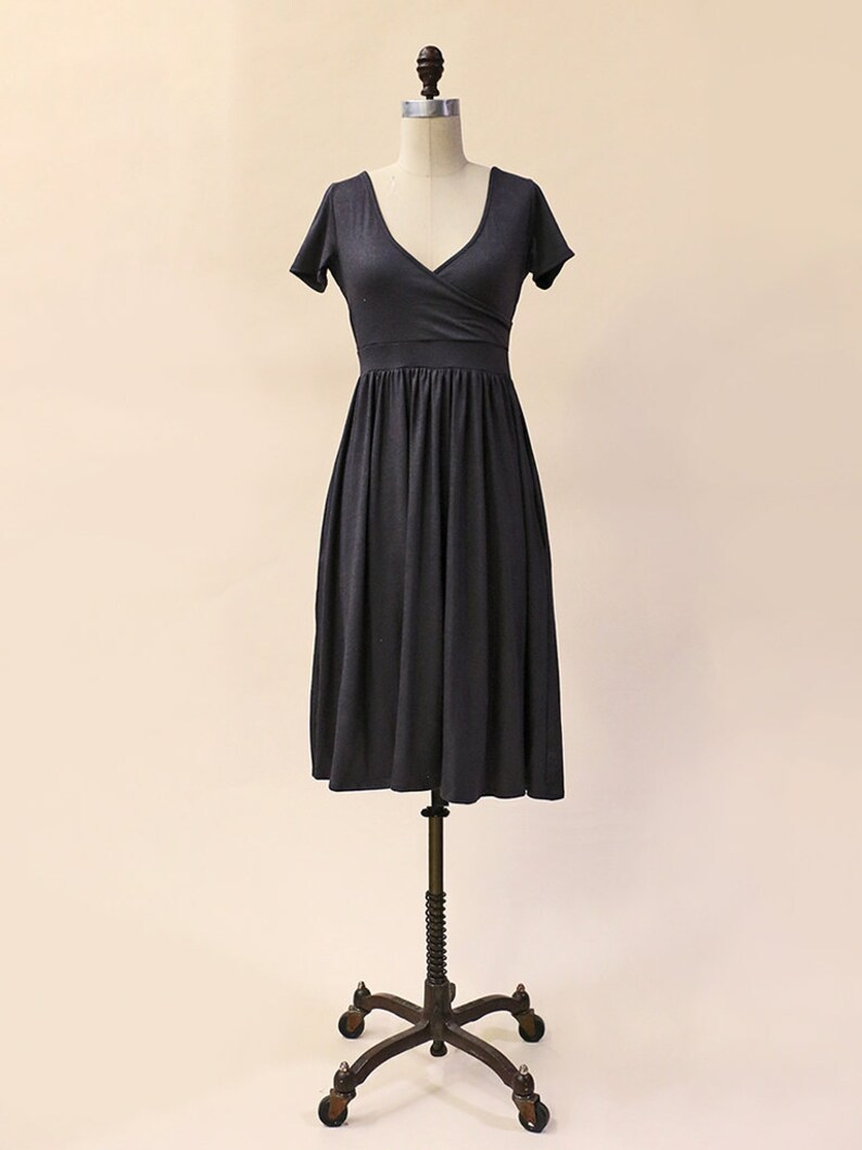 May include: A charcoal gray wrap dress with short sleeves and a V-neckline. The dress has a fitted bodice and a flowing skirt.