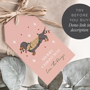May include: Pink printable gift tag with a cartoon dachshund wearing a plaid scarf and Christmas lights. The text reads "Merry Christmas Love, The Pacry's".