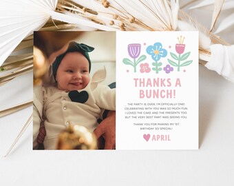 May include: A birthday card with a photo of a baby wearing a green headband and a white outfit. The card has the text "THANKS A BUNCH!" and a message about the baby's first birthday. Floral illustrations in pink, blue, and purple are also present.