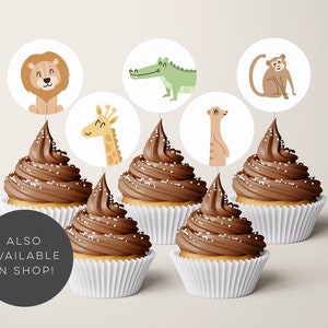 Pode incluir: Seis cupcakes de chocolate com cobertura branca e granulado, coroados com toppers redondos de papel para cupcakes que representam animais: um le&atilde;o, uma girafa, um crocodilo, um suricato e um macaco. O texto "ALSO AVAILABLE IN SHOP!" est&aacute; em um c&iacute;rculo preto.