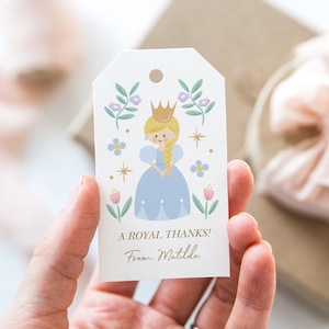 May include: A white gift tag with a cartoon princess wearing a blue dress and a gold crown. The tag has a floral design and the text "A Royal Thanks! From Matilda".