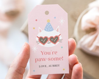Può includere: Etichetta regalo rosa con un gatto bianco che indossa un cappello da festa e occhiali a forma di cuore. Il testo dice "You're paw-some! LOVE, AUBREY".