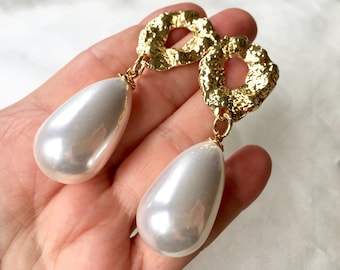 May include: Gold tone earrings with a textured, irregular shape and a large, white pearl drop.