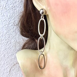 May include: Silver chain earrings with three oval links and a small round ball at the top.