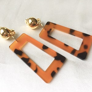 May include: A pair of gold tone clip-on earrings with a rectangular tortoiseshell design.