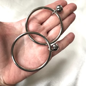 May include: Two silver hoop earrings with a ball at the end of each hoop.