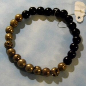May include: A black and gold beaded bracelet with a mix of round and textured beads.