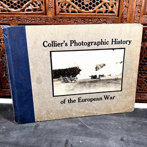 May include: A hardcover book titled Collier's Photographic History of the European War with a tan cover and a dark blue spine. The front cover features a black and white photograph of artillery in a field during a military conflict.