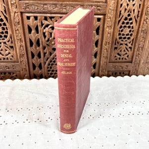 May include: A maroon hardcover book titled Practical Anesthesia for Dental and Oral Surgery by Seldin. The spine features gold lettering and a small circular emblem at the bottom. The book is standing upright with a visible cream-colored page edge.